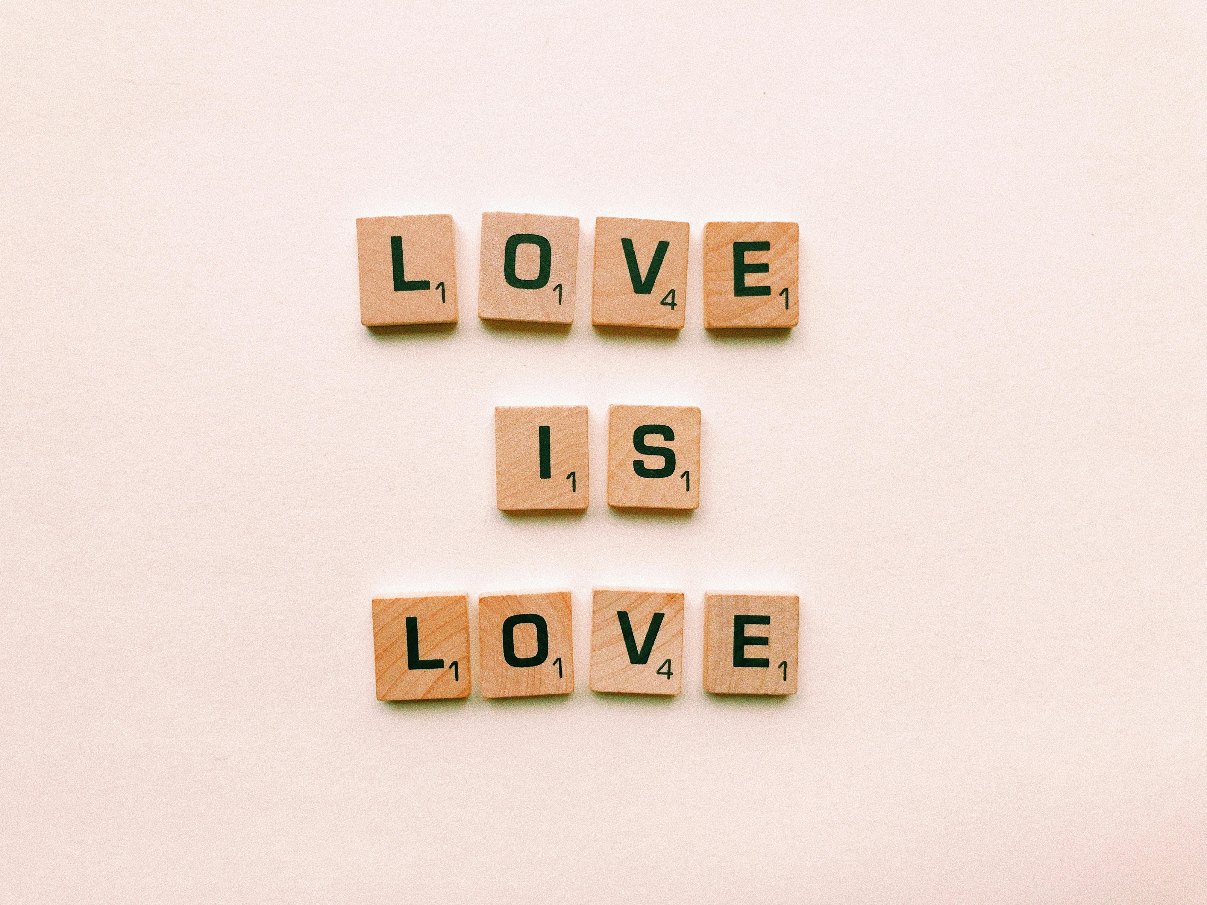 Wooden letter tiles forming 'Love is Love', symbolizing inclusion and pride.