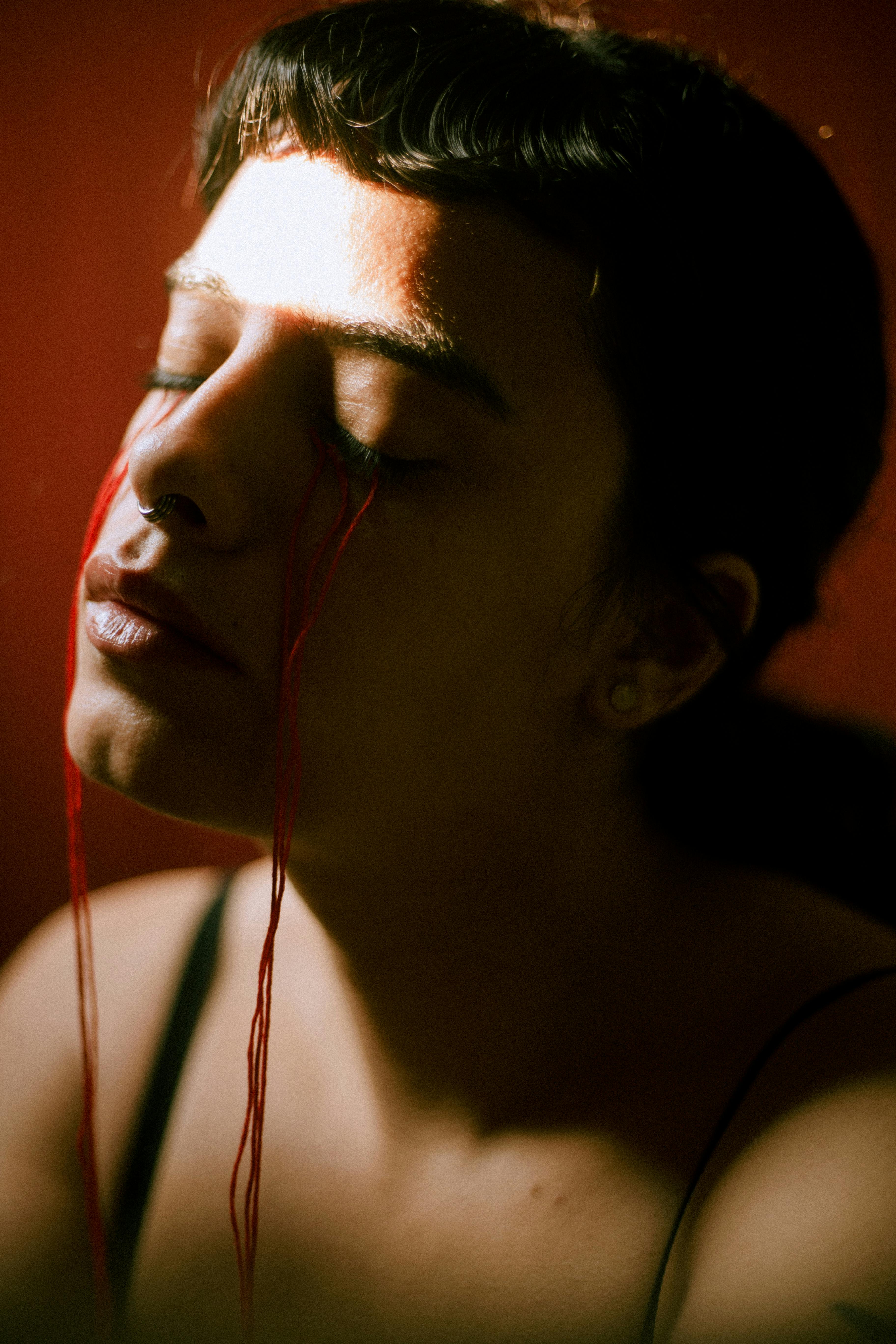 Artistic portrait of a woman with red threads symbolizing emotional depth and introspection.