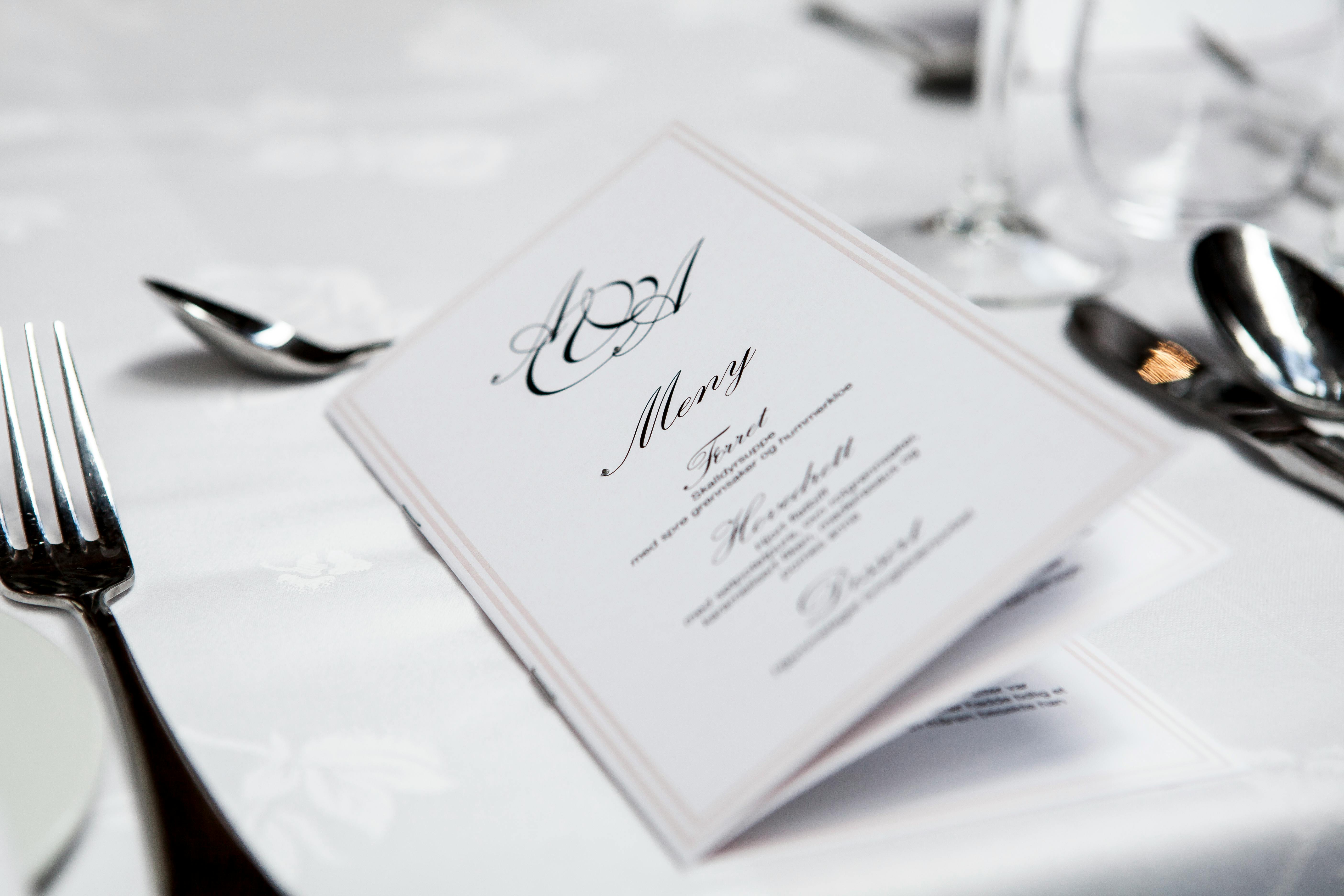 Close-up of a refined dining table with menu and silverware, showcasing elegance in a formal restaurant setting.