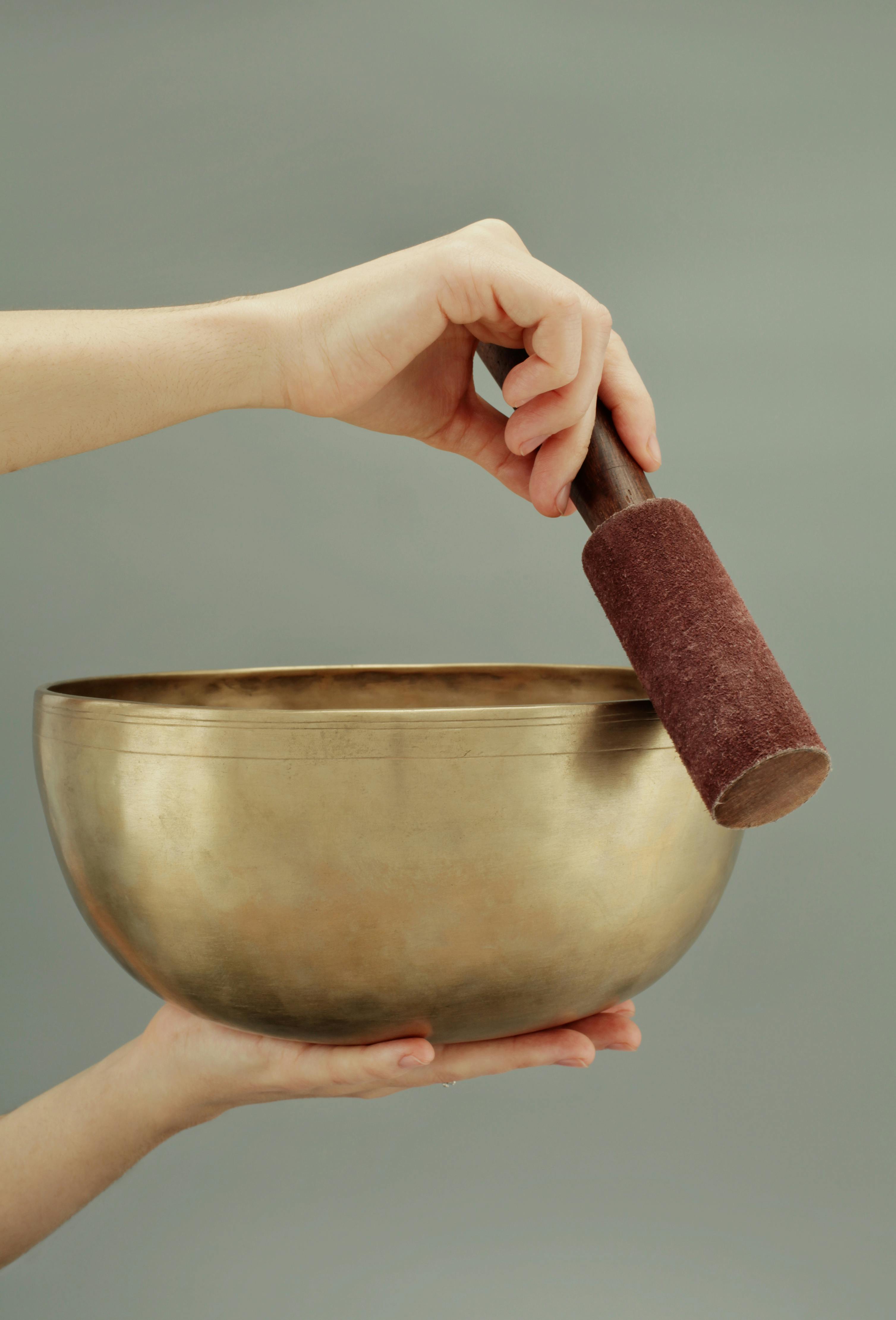 A close-up of hands holding a Tibetan singing bowl, used for sound healing and meditation.