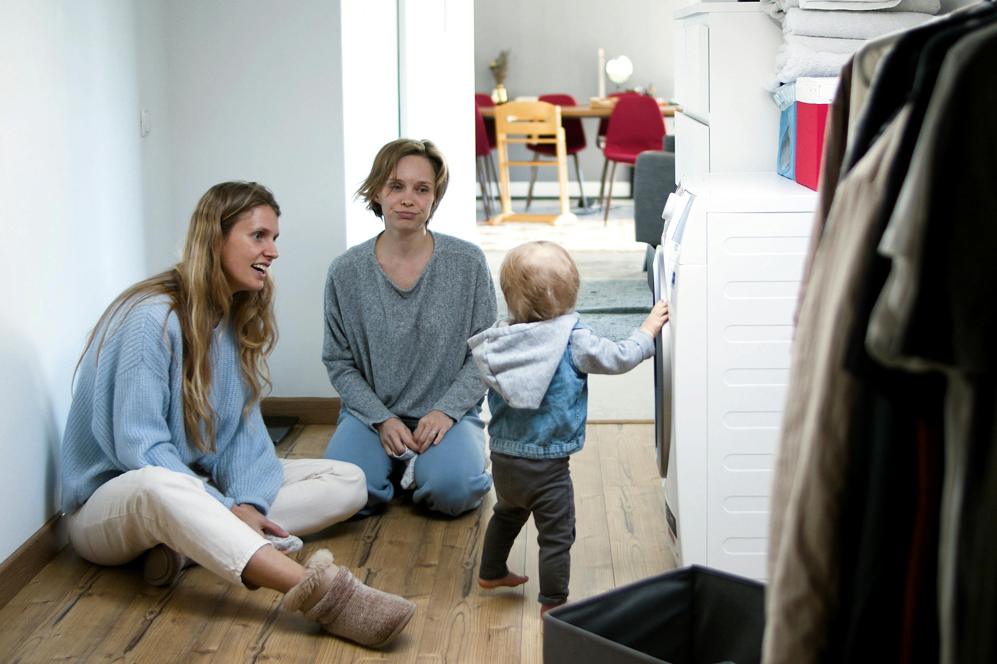 A mother and friend enjoy quality time with a toddler in a cozy home setting.