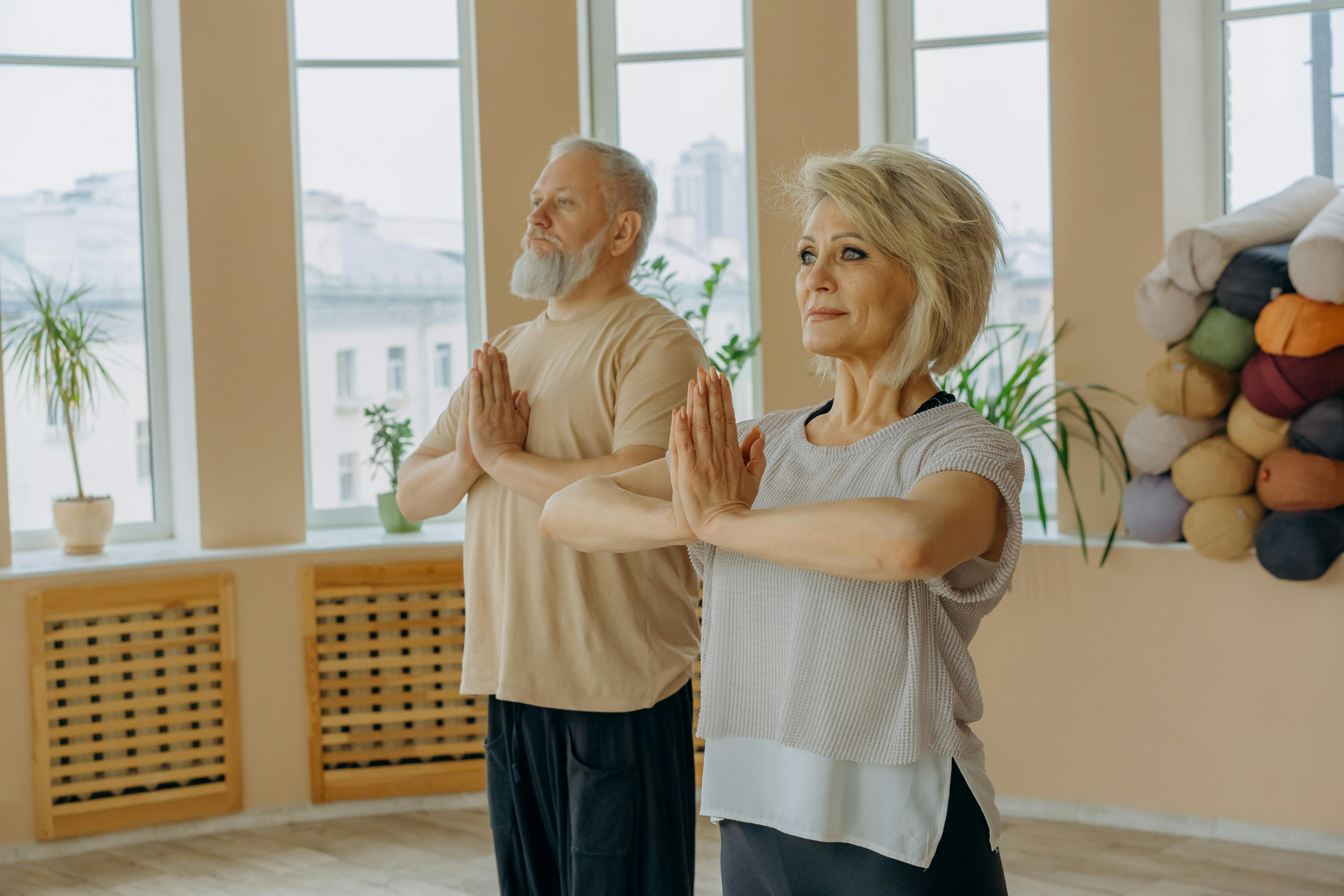 Senior couple in a yoga studio practicing meditation poses, focusing on mindfulness and health.