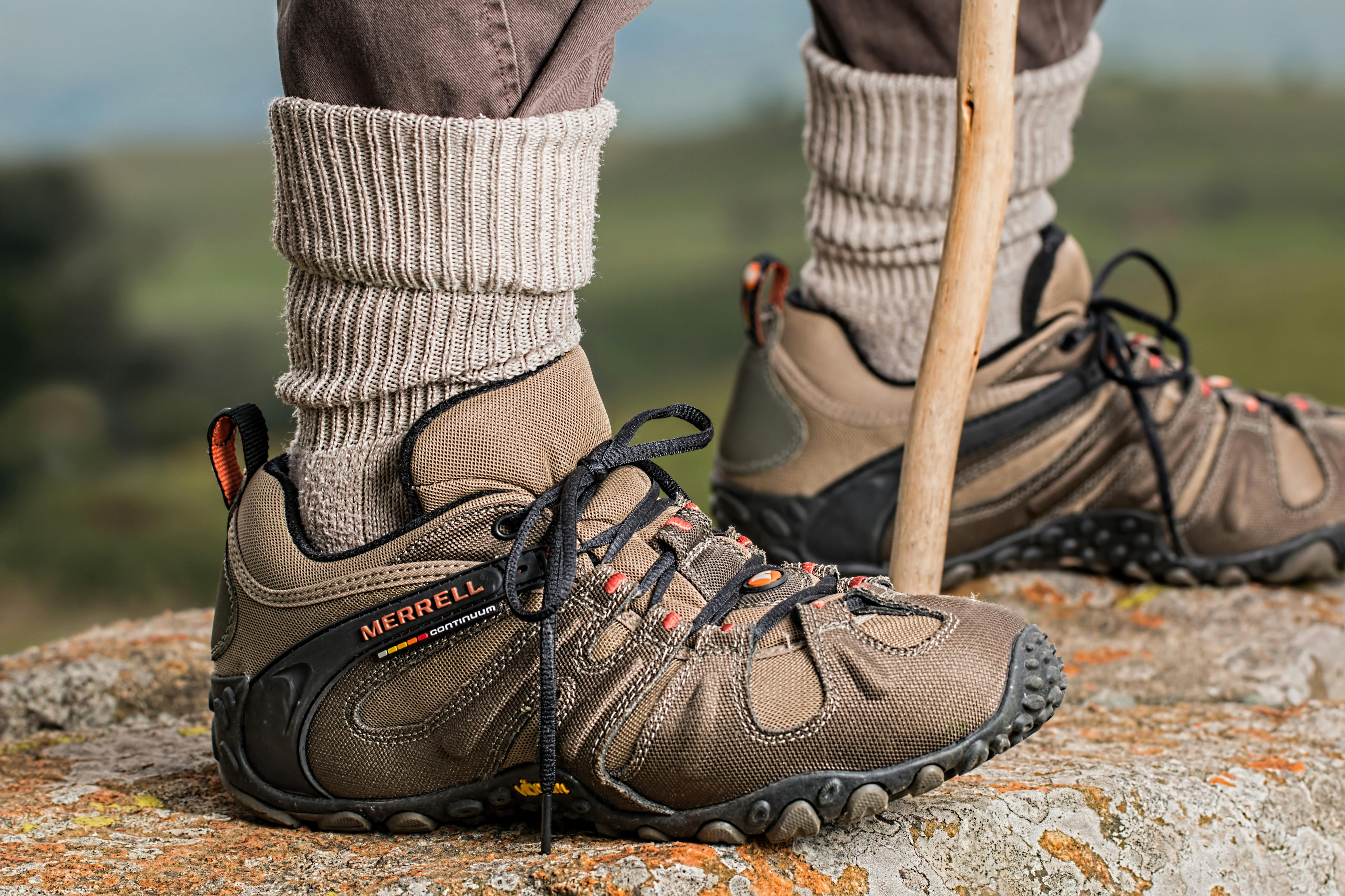 Hiking boots by Merrell on a rock edge, featuring outdoor adventure gear.