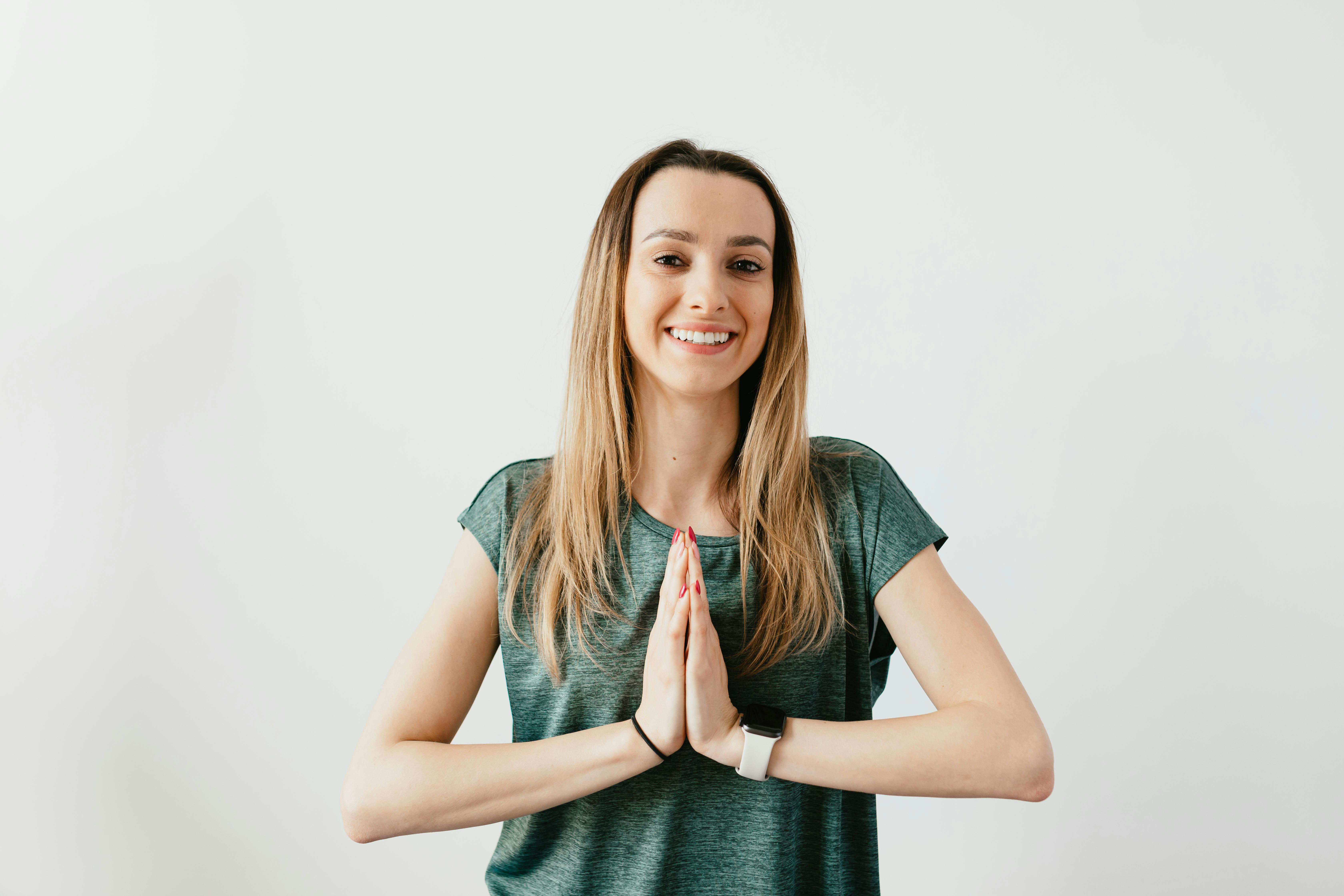 Cheerful woman in green shirt practicing yoga indoors, embracing peace and wellness.