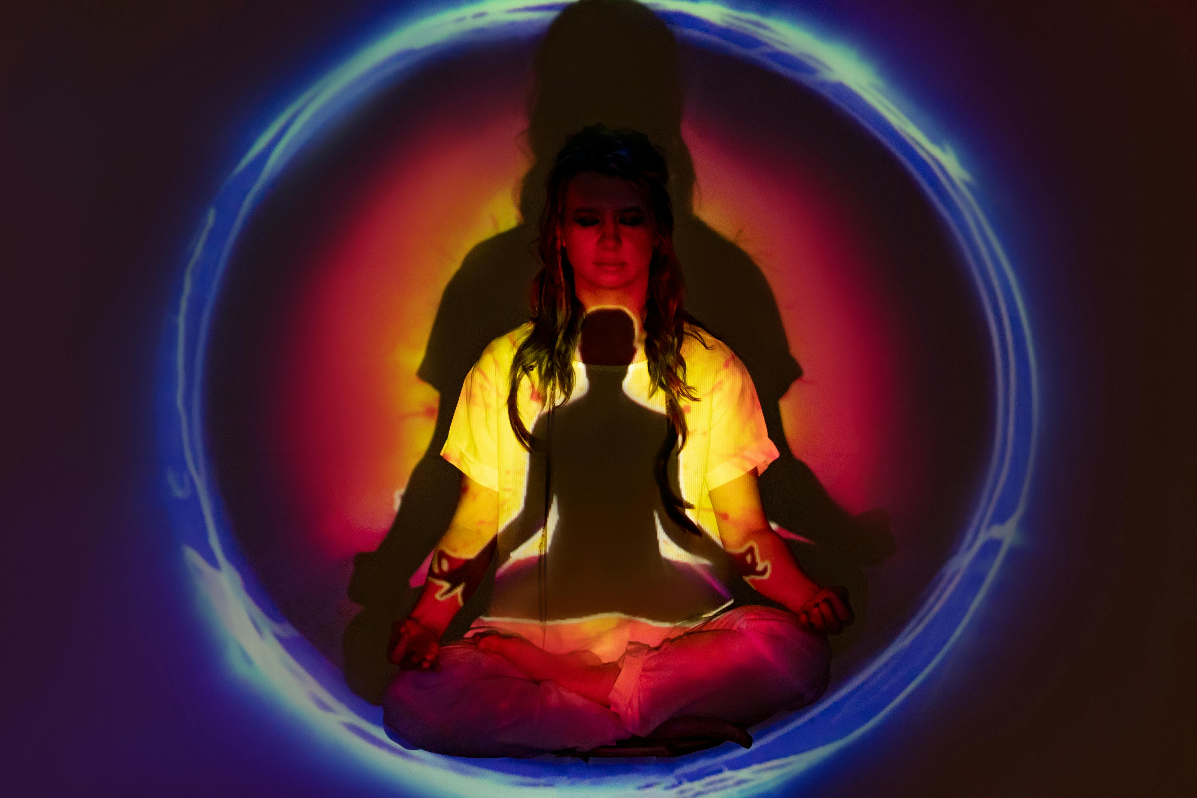 A woman in meditation surrounded by colorful auric light, creating a spiritual atmosphere.