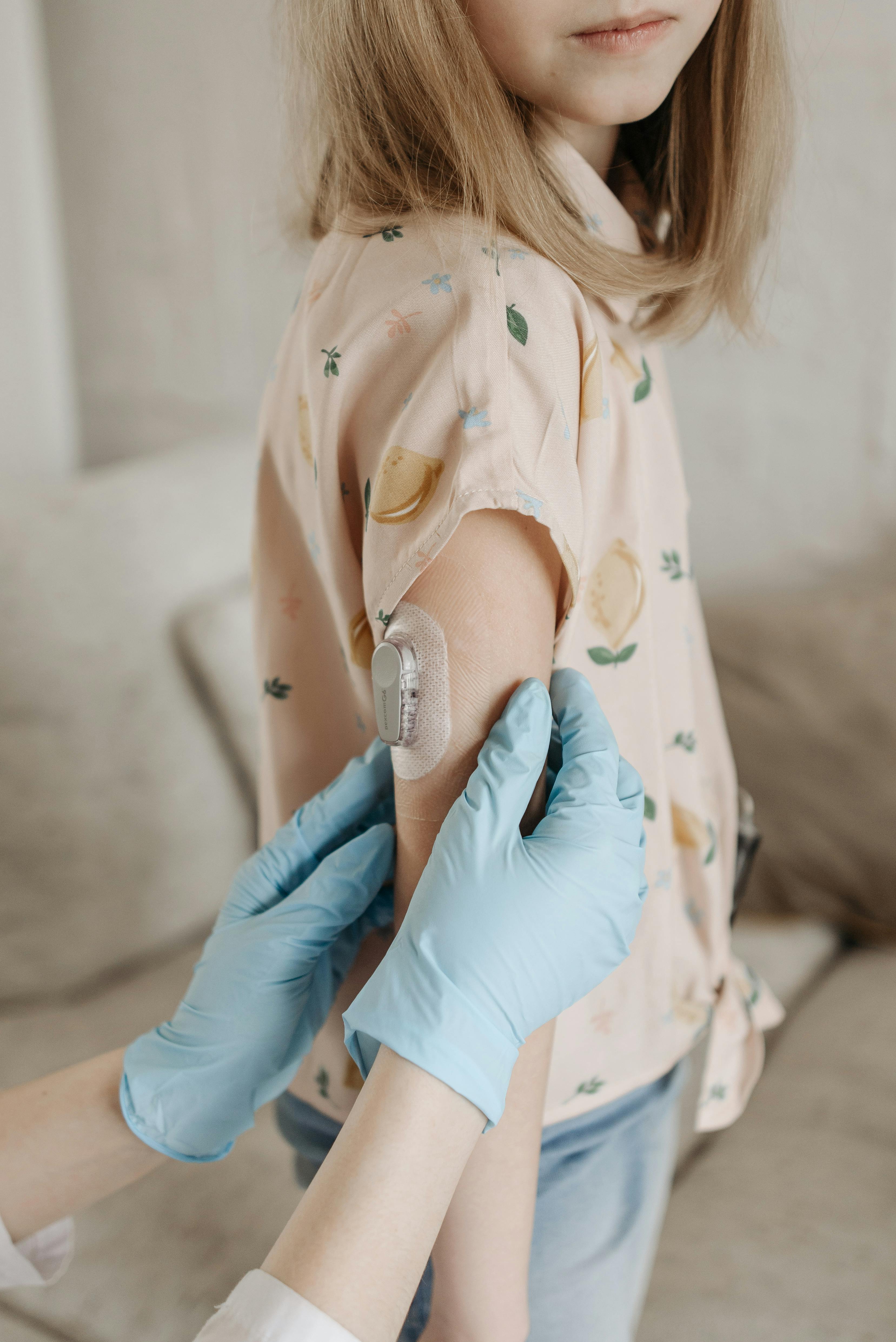 A healthcare professional adjusts a glucose monitor on a child's arm, highlighting diabetes care.