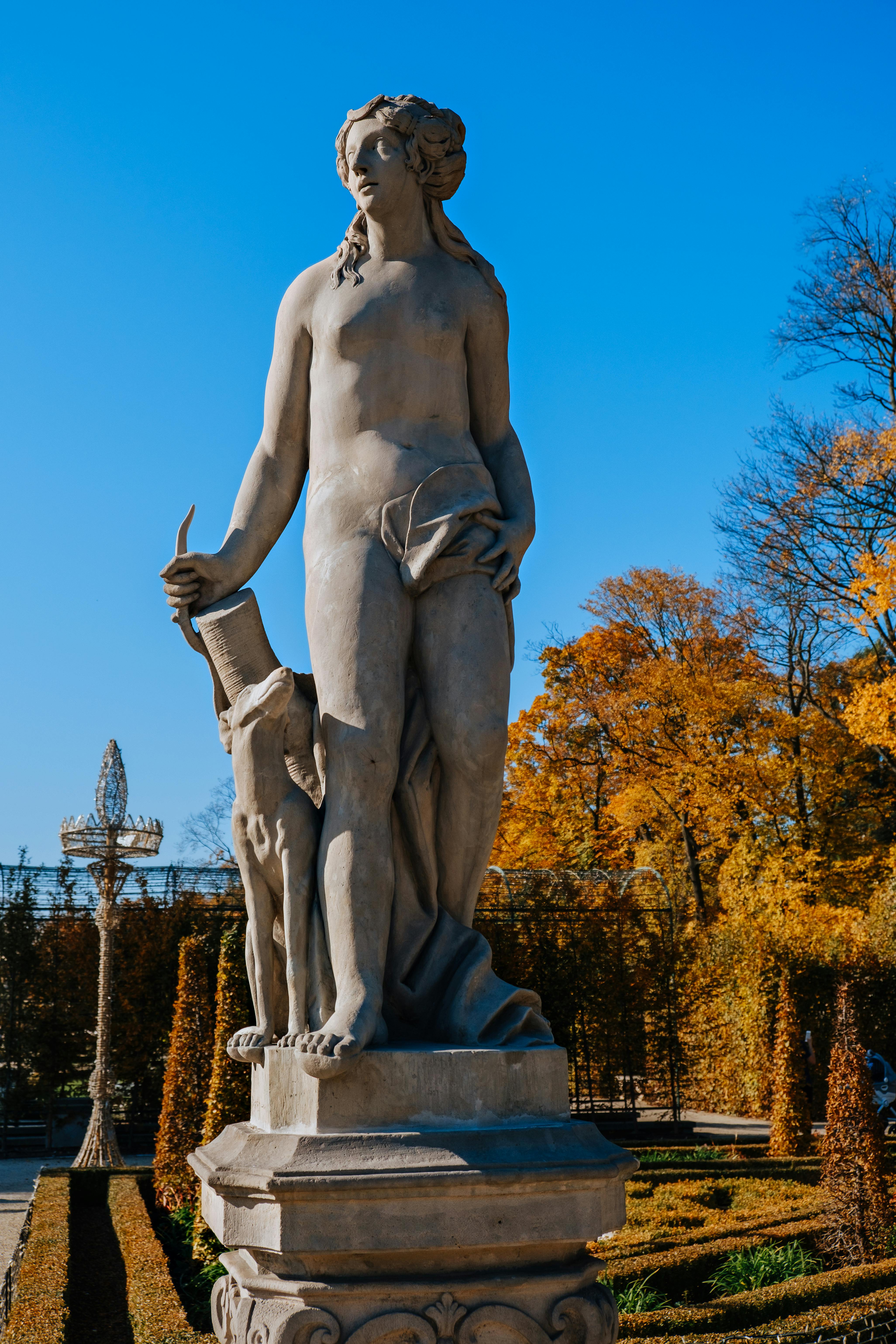 Marble statue of a classical figure in an autumn garden, capturing artistic elegance.