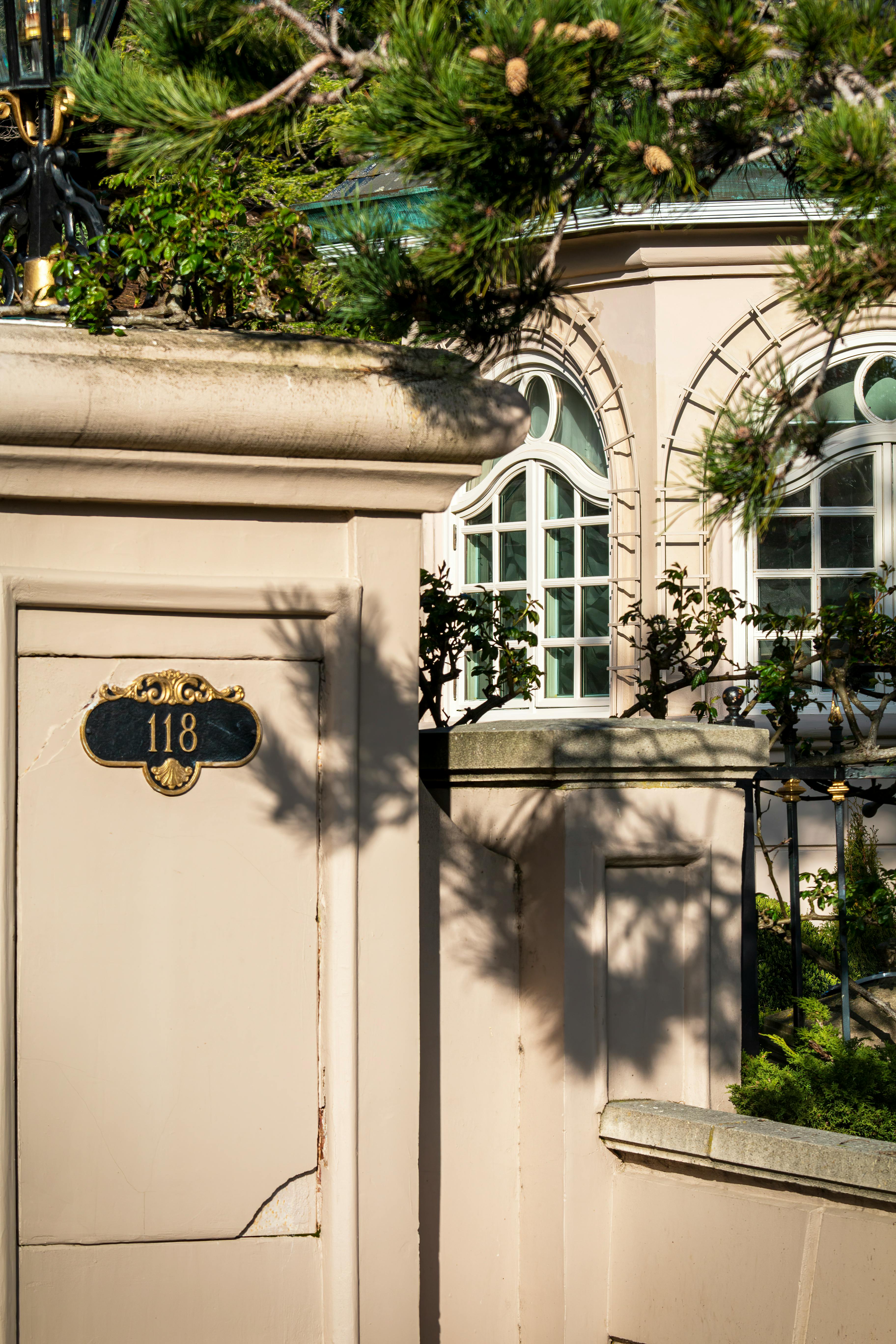 Charming villa entrance with sunlit windows and greenery, evoking elegance and warmth.