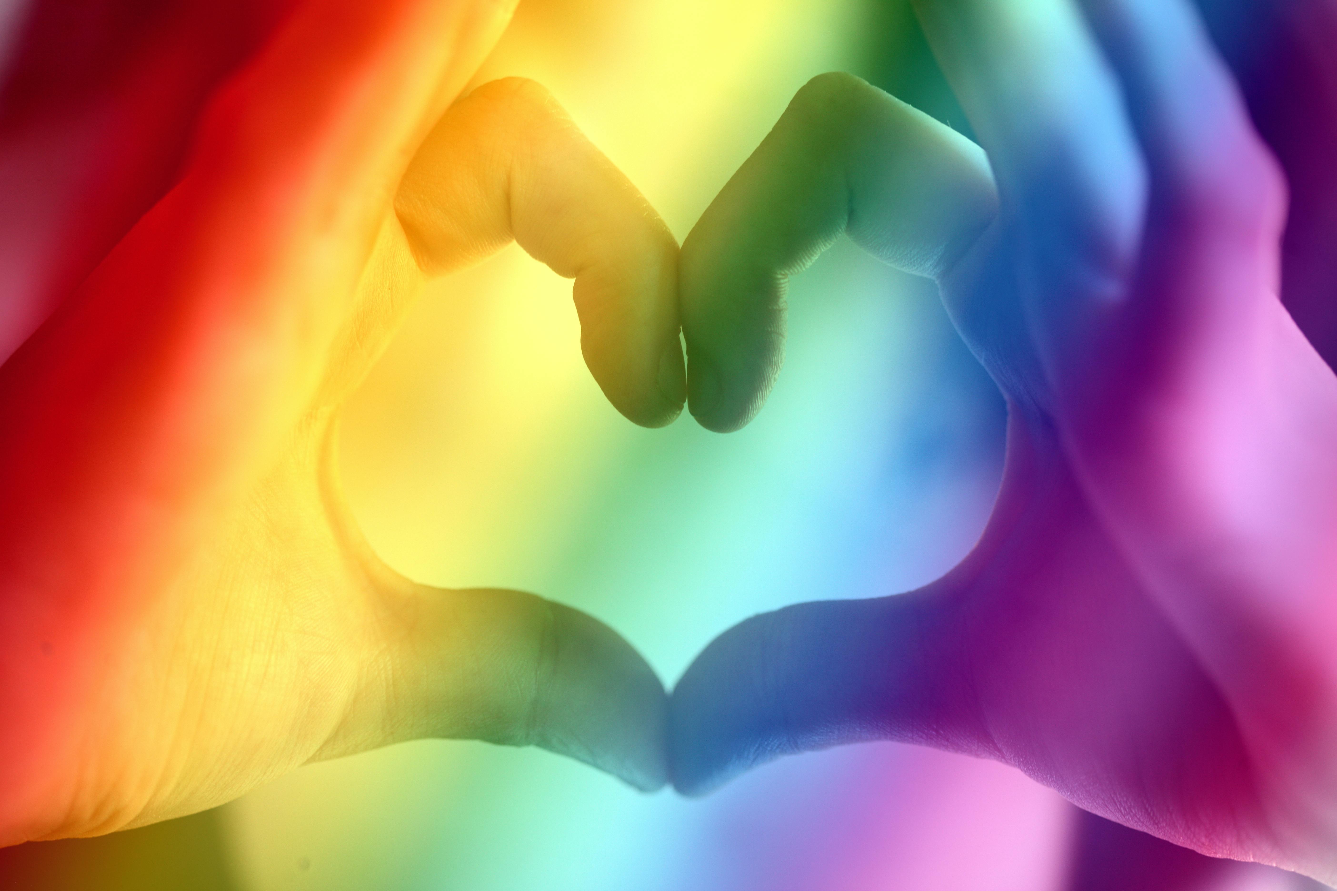 Hands forming a rainbow heart shape, symbolizing love, unity, and LGBTQ pride.