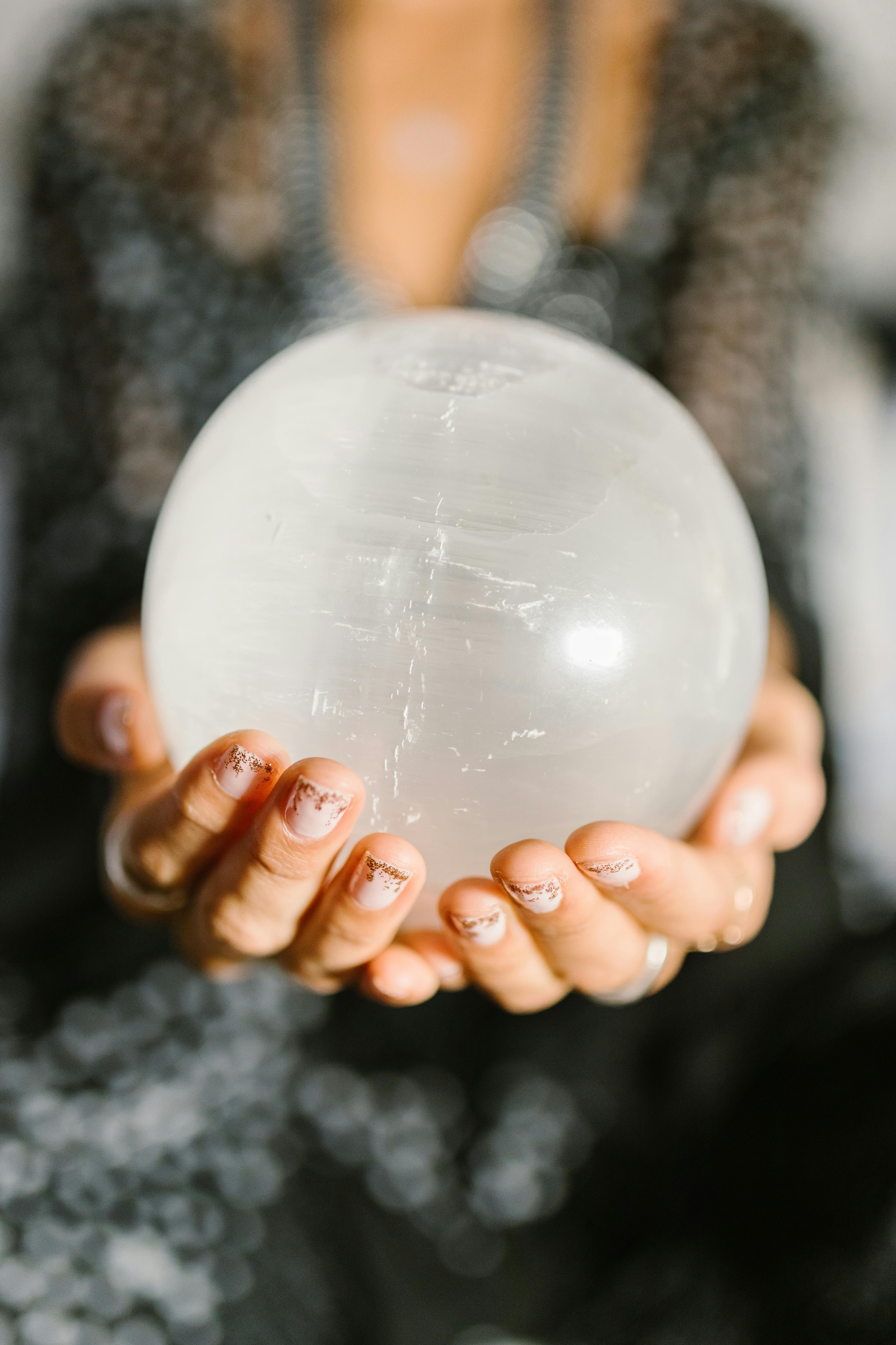 Close-up of hands holding a clear crystal ball, ideal for spiritual or metaphysical themes.